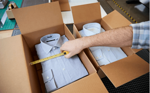 Person measuring shirt inside of a cardboard box.